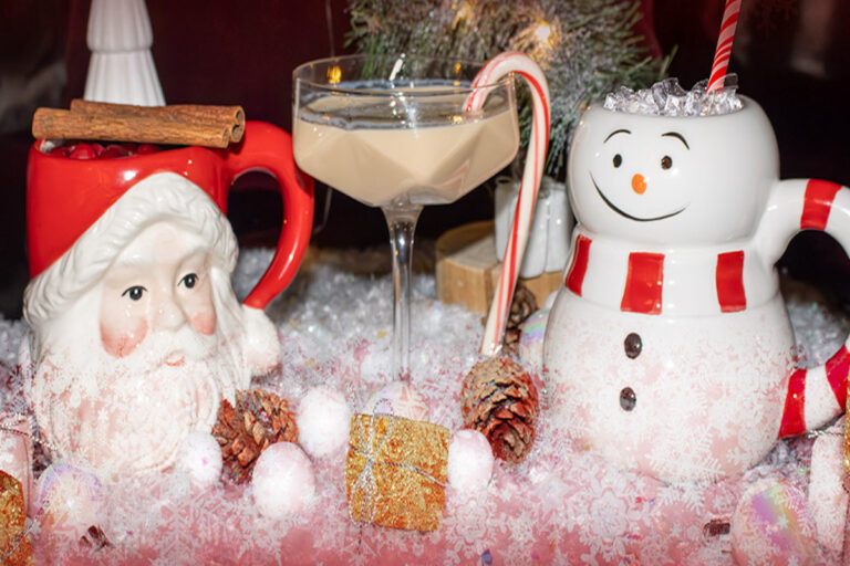a glass of liquid next to a snowman figurine