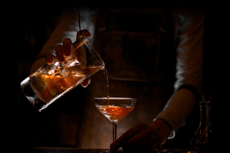 a person pouring a drink into a glass