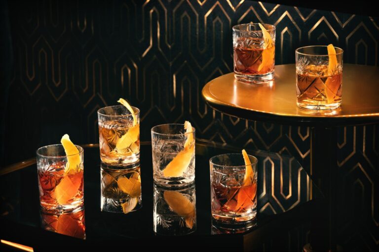 a group of glasses with liquid and orange peels on a table